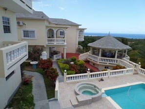 A two-story building with a pool, a gazebo, and a view of the ocean. - The Royal Kensington Villa (Montego Bay)