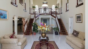 A spacious foyer with a grand staircase, two sofas, a vase of flowers, and potted plants. - The Royal Kensington Villa (Montego Bay)