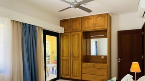 Un dormitorio con cama, armario, ventilador de techo y puerta que da a un espacio exterior.