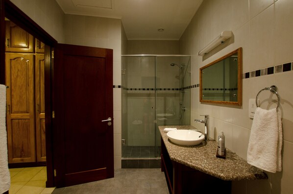Une salle de bain avec une douche à parois de verre, un lavabo avec un miroir et une serviette suspendue à un porte-serviettes.