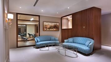 A modern room with two patterned sofas, a glass coffee table, and a wooden accent wall.