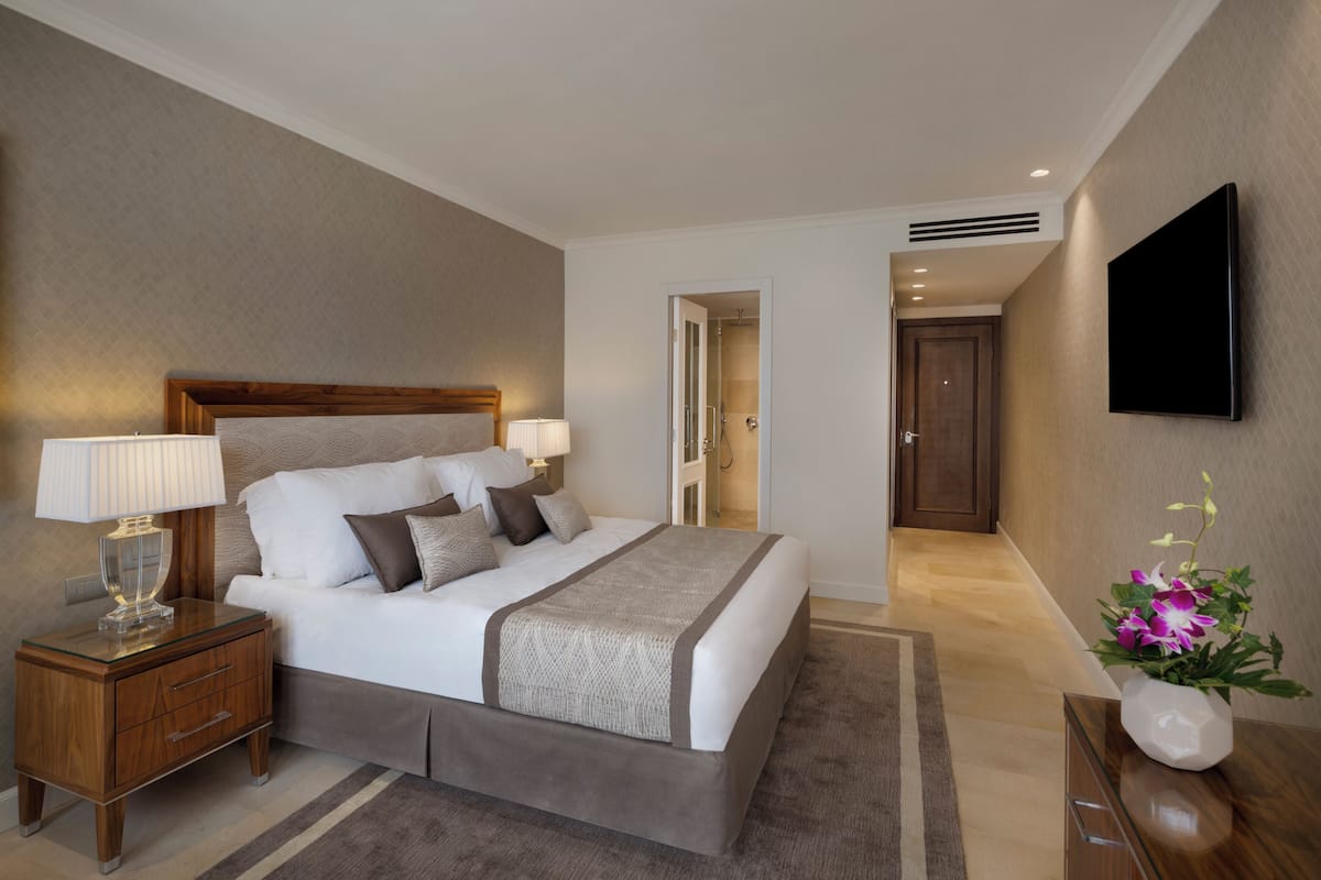 A hotel room with a bed, bedside tables, a TV, and a bathroom door.