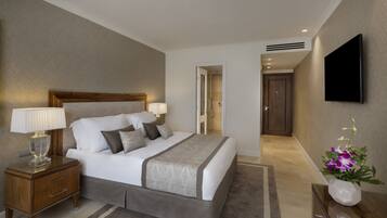 A hotel room with a bed, bedside tables, a TV, and a bathroom door.