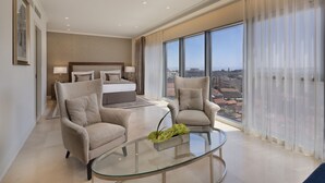 A modern hotel room with a large bed, two armchairs, a glass coffee table, and a city view. - Herbert Samuel Jerusalem (Jerusalem)