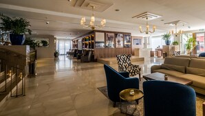 A spacious lobby with a modern design, featuring a reception desk, seating area with sofas and chairs, and a bookshelf with framed pictures. - Herbert Samuel Jerusalem (Jerusalem)