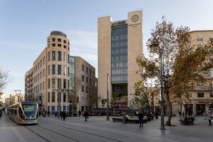 Una calle urbana moderna con un tranvía, edificios y peatones.