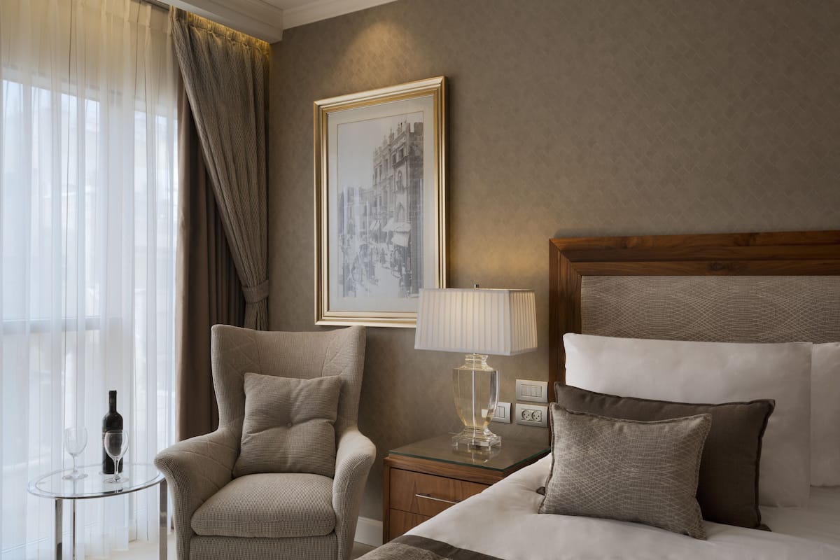 Classic design with a large bed, armchair, and bedside table, creating a cozy atmosphere.