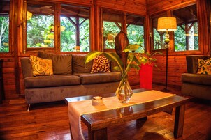 A cozy room with a wooden interior, a sofa, a coffee table, and a vase with plants.