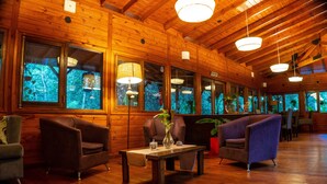 Un intérieur en bois avec une table, des chaises et de grandes fenêtres, le tout également en bois.