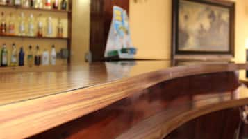 A bar area with shelves of bottles, a framed picture on the wall, and a wooden counter.