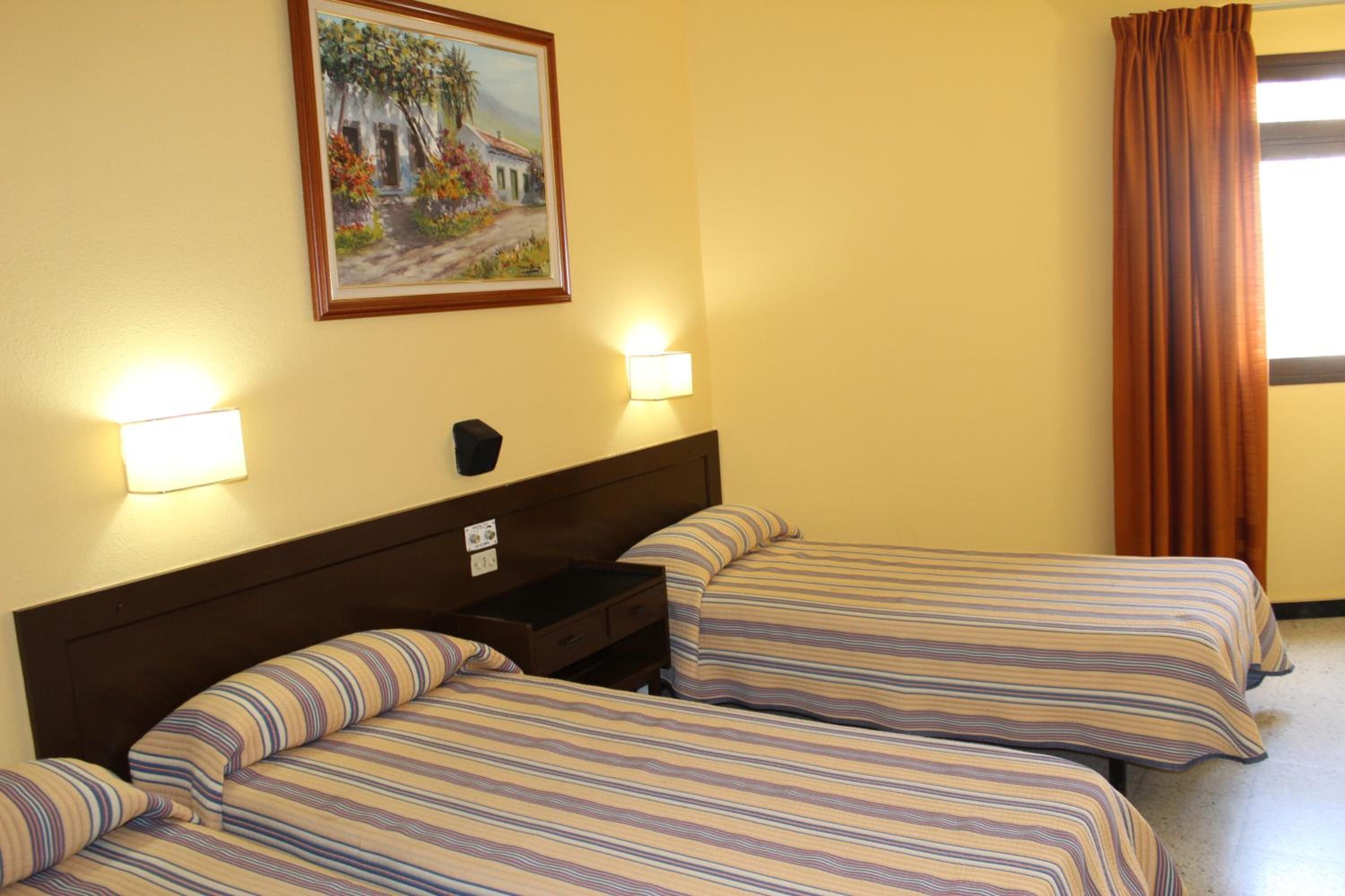 A hotel room with two beds, a nightstand, a painting on the wall, and a window with curtains.