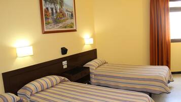 A hotel room with two beds, a nightstand, a painting on the wall, and a window with curtains.