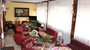 Una sala de estar amplia con sofás de cuero, una mesa de centro y plantas en macetas.