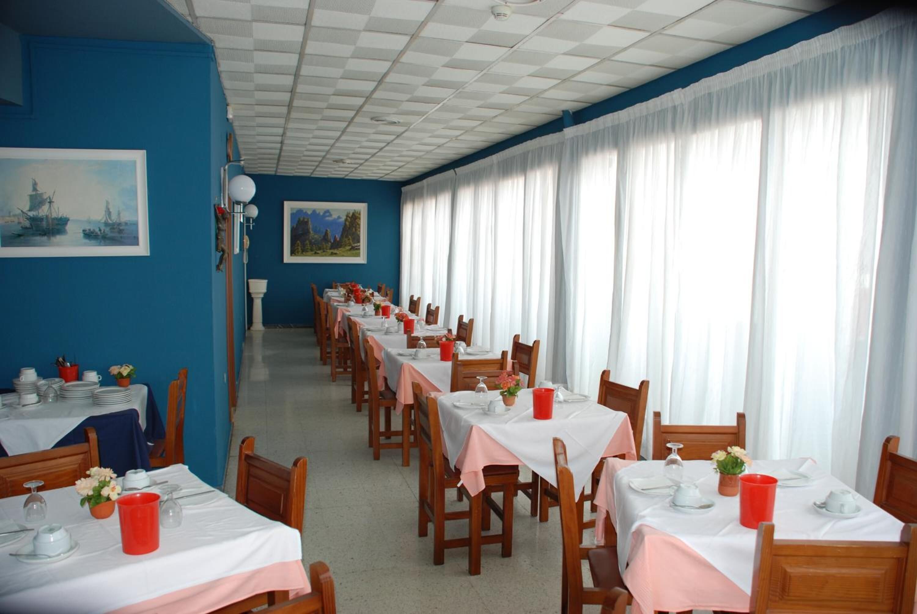 A dining area with tables set for service, blue walls, and artwork.