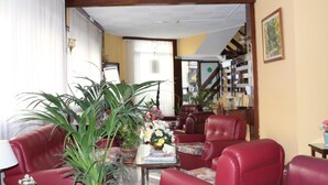 Un salón con sofás de cuero rojo, una mesa de centro con un jarrón de flores y una estantería al fondo.