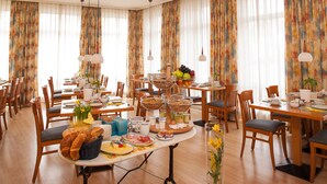 A dining area with multiple tables set for breakfast, featuring bread, fruits, and beverages. - Hotel zum Deutschen Eck (Meerbusch)