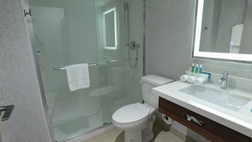 Une salle de bain moderne avec une douche à parois de verre, des toilettes blanches et un lavabo équipé de produits de toilette.