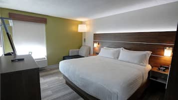 Ein Hotelzimmer mit einem großen Bett, einem Schreibtisch, einem Stuhl und einem Nachttisch mit Lampe.