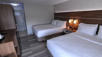 Habitación de hotel con dos camas, un armario de madera y un escritorio con lámpara.