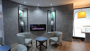 A modern lounge area with a flat-screen TV, seating, and decorative vases. - Holiday Inn Express & Suites Toronto Airport West by IHG (Mississauga)