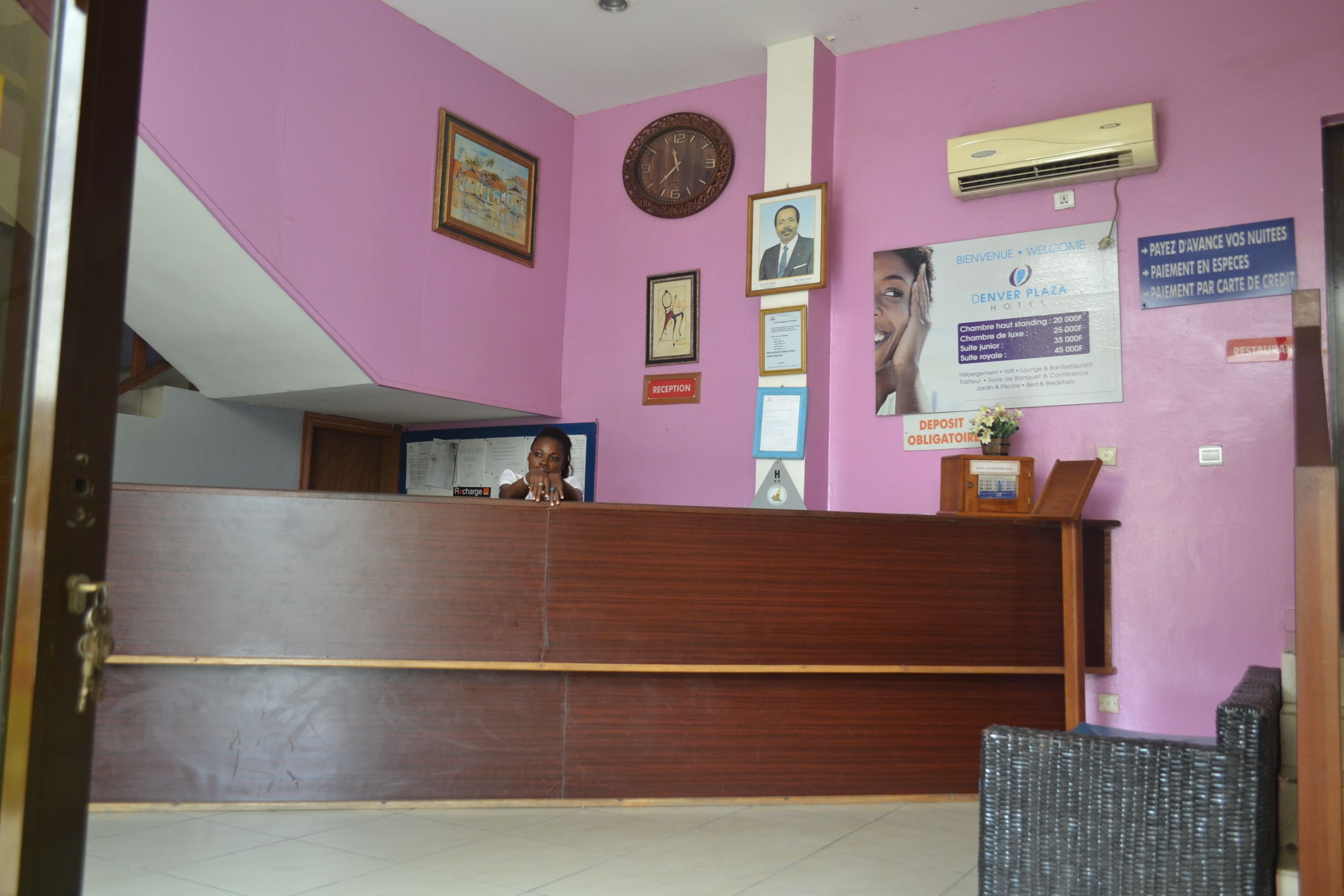 A reception area with a wooden reception desk, a clock, framed pictures, and a sign indicating a mandatory deposit.