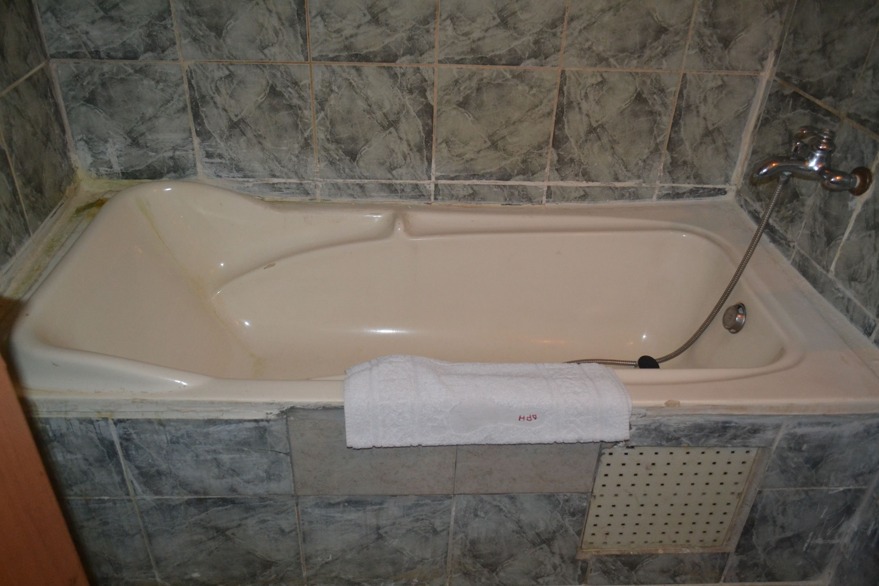 Una bañera con cabezal de ducha, una toalla y un tapón de desagüe.