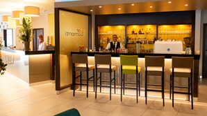 Eine Bar mit Bartender, Barhocker und einer Auswahl an Flaschen und Gläsern.
