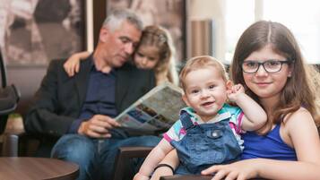 Eine Familie sitzt an einem Tisch in einem Raum, an der Wand hängt eine Karte.