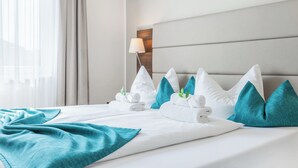 Un lit bien fait, avec des oreillers blancs et turquoise, un plaid turquoise et une lampe sur une table de chevet.