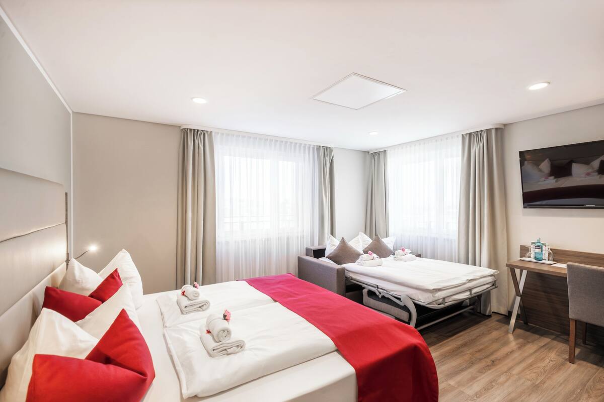 Ein Hotelzimmer mit zwei Betten, einem Schreibtisch und einem Fernseher.