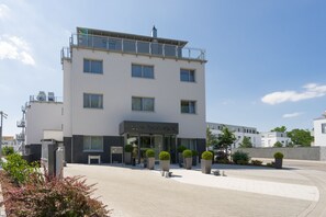 Un hôtel moderne doté d’un toit plat, de grandes fenêtres et d’un hall d’entrée bien entretenu agrémenté de plantes en pot.