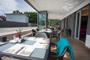 Un espace extérieur aménagé pour les repas, avec des tables et des chaises, un chemin et un bâtiment en arrière-plan.