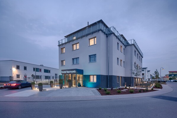 Un hôtel moderne à la façade sobre, doté de grandes fenêtres et d’une entrée bien visible.