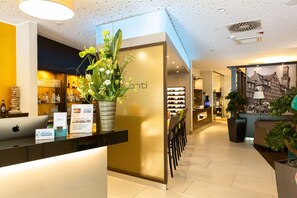 Un espace d’accueil au design moderne, comprenant un comptoir de réception, une plante en pot et un panneau fixé au mur.