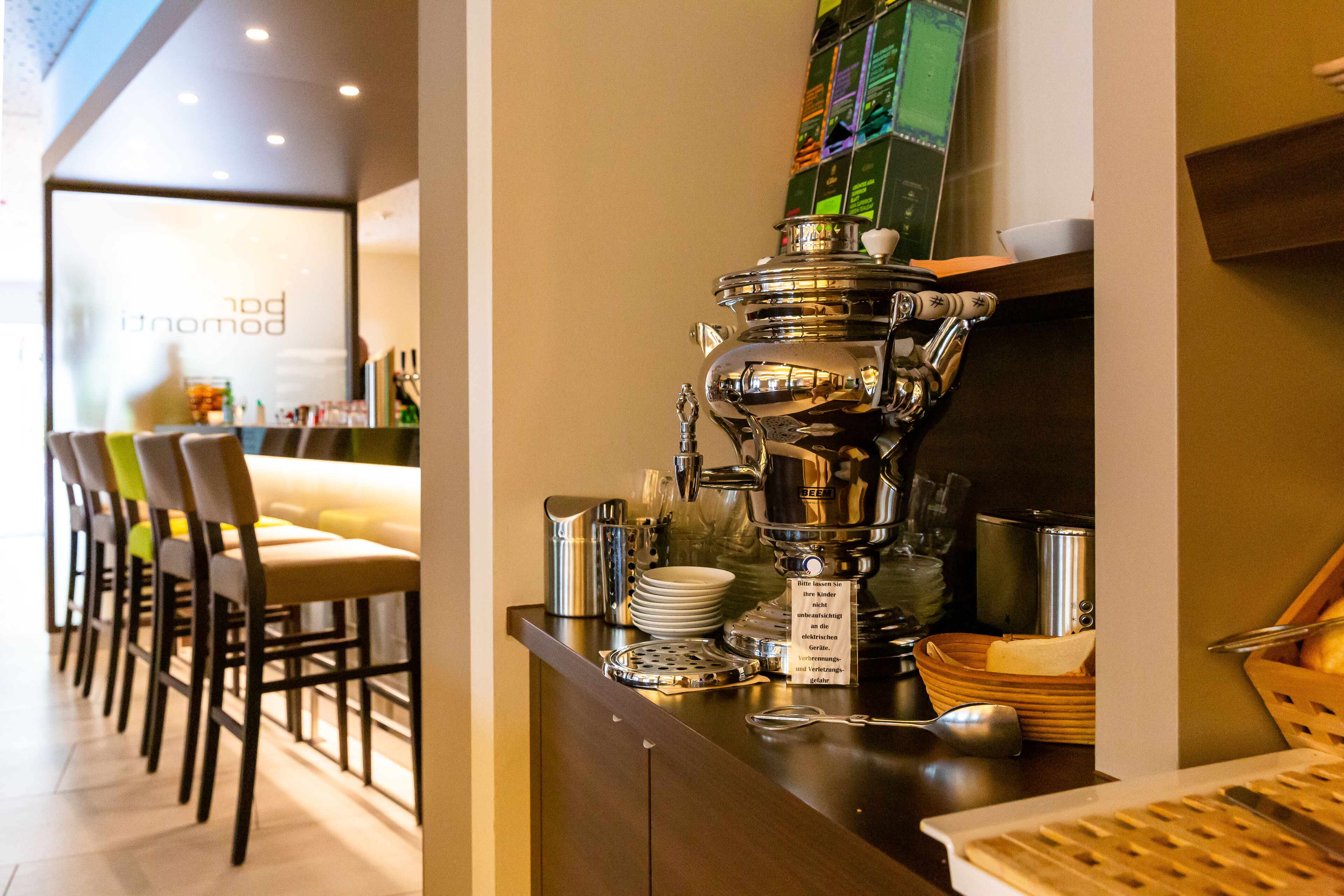 A coffee station with a coffee machine, cups, and a menu board.