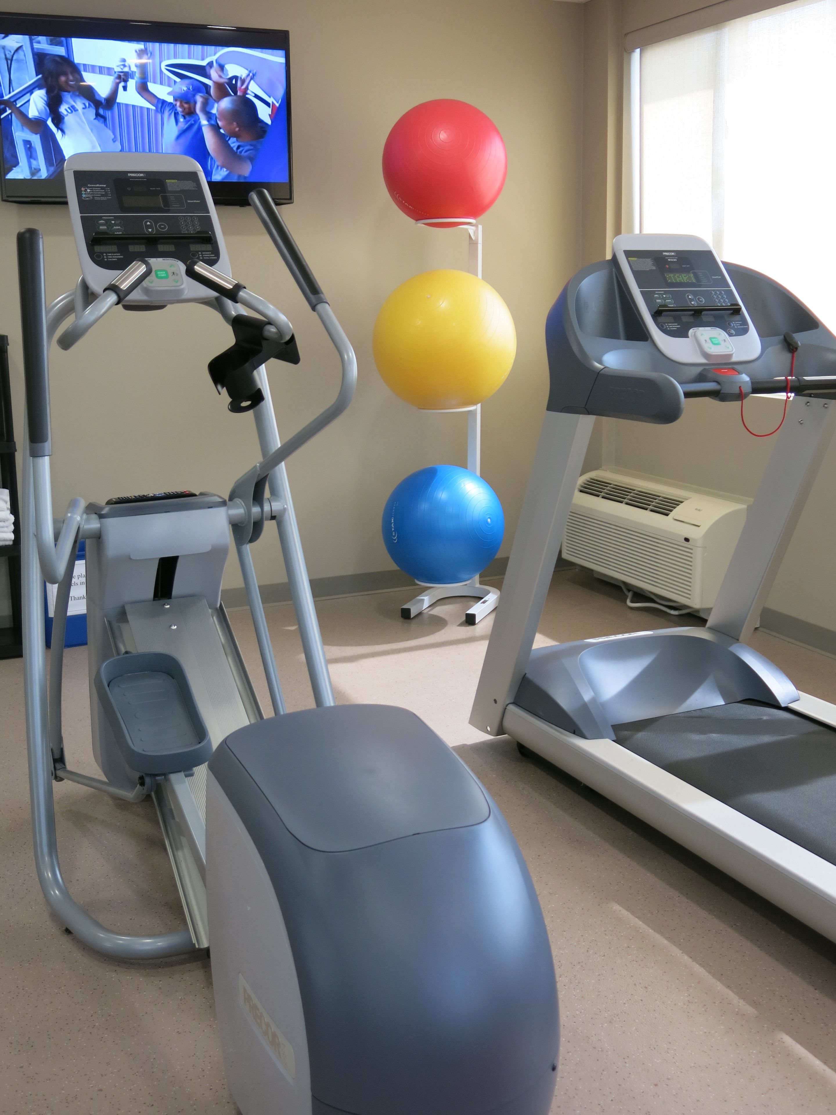 A gym with treadmills, an elliptical, and exercise balls.