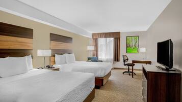 A hotel room with two beds, a desk, a chair, a television, and a painting on the wall.