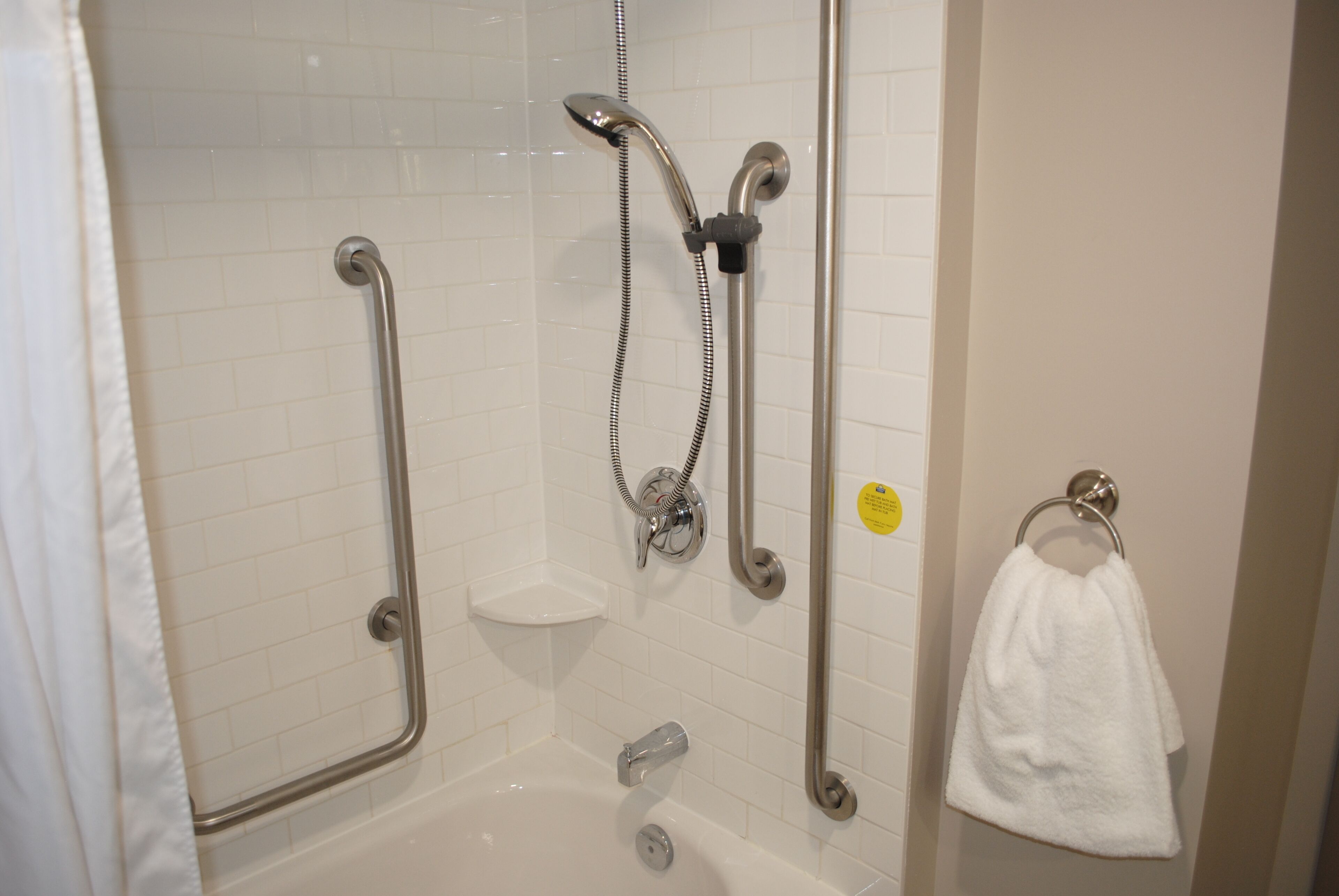 A bathroom with a shower, grab bars, a towel rack, and a soap dish.