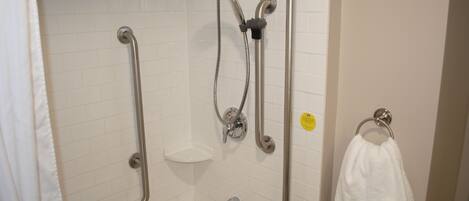 A bathroom with a shower, grab bars, a towel rack, and a soap dish.