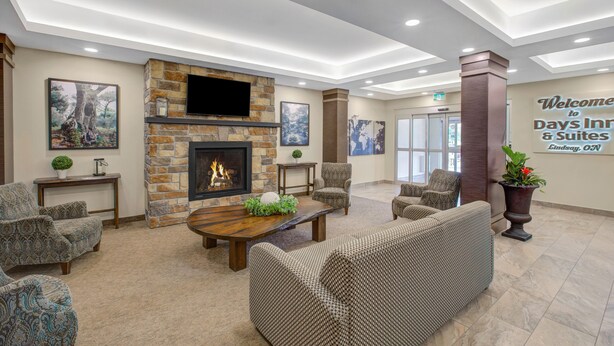 A lobby with a fireplace, comfortable seating, and a welcome sign. - Days Inn & Suites by Wyndham Lindsay (Kawartha Lakes)