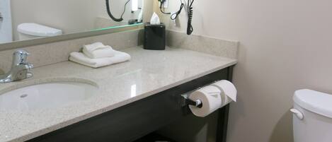 A bathroom with a sink, mirror, towel rack, toilet, and a shelf with towels.