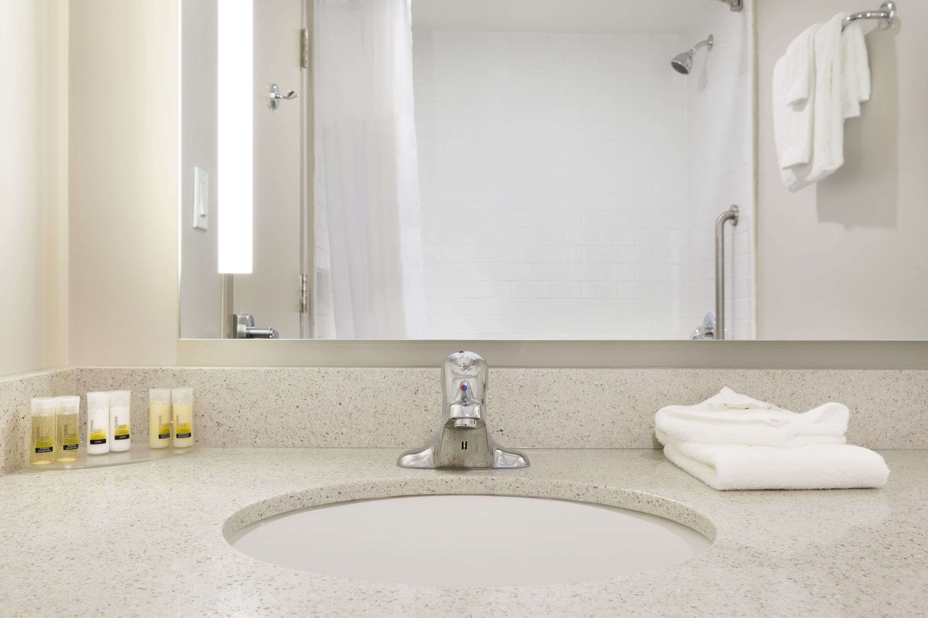 A bathroom with a sink, mirror, and towel rack.