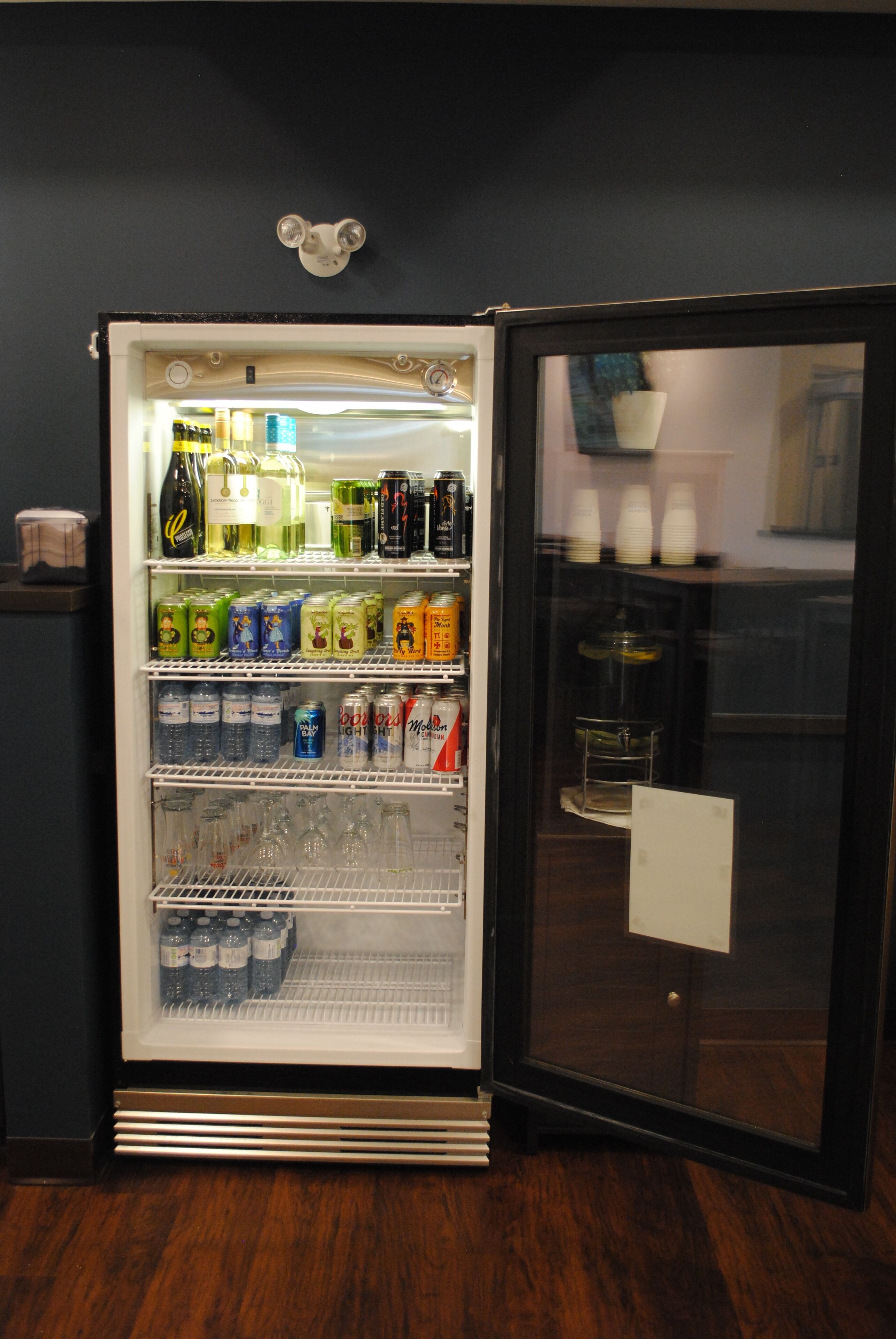 Un refrigerador lleno de diversas bebidas y aperitivos, como botellas, latas y cajas.