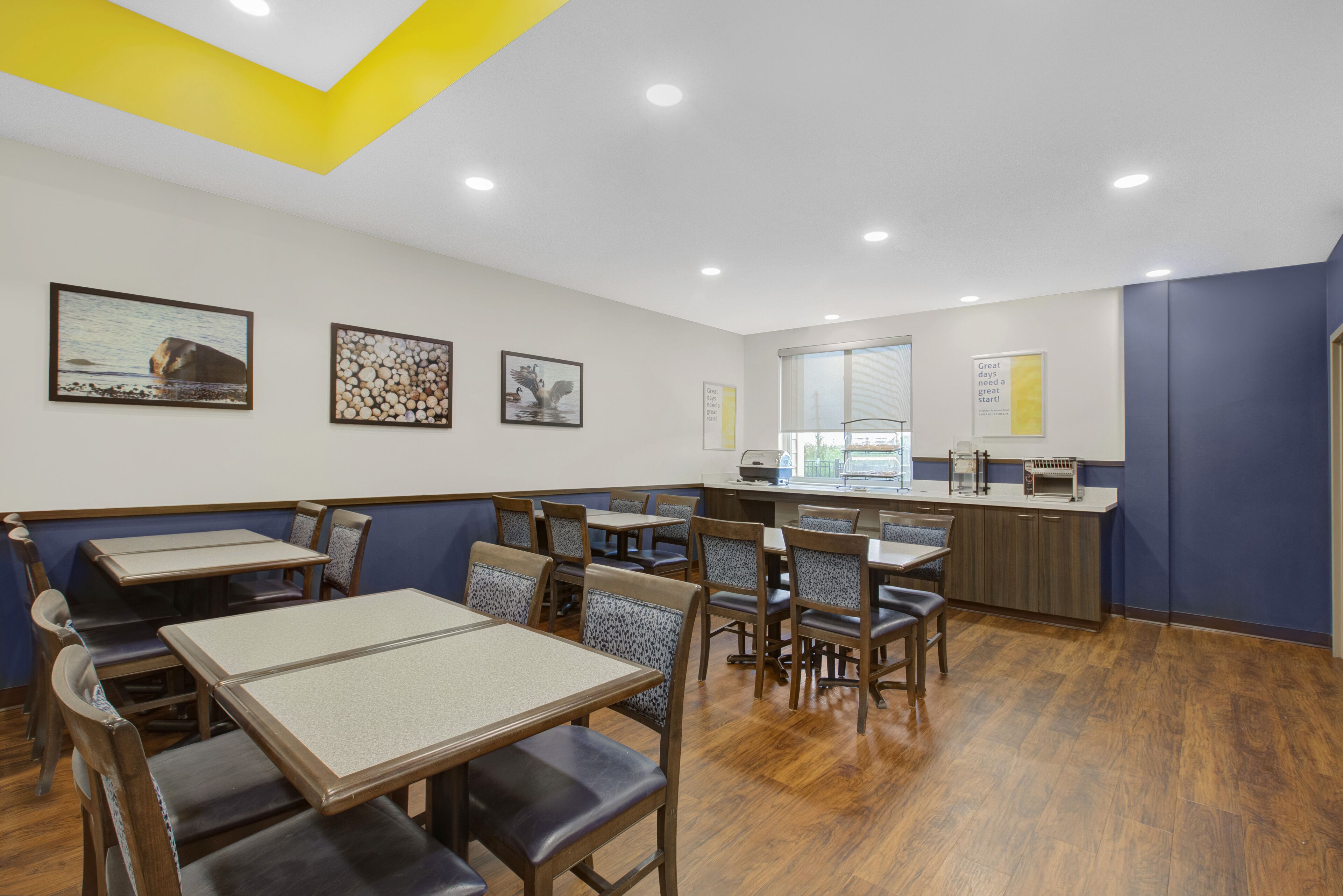 A restaurant with booths and tables, wooden flooring, and artwork on the walls.