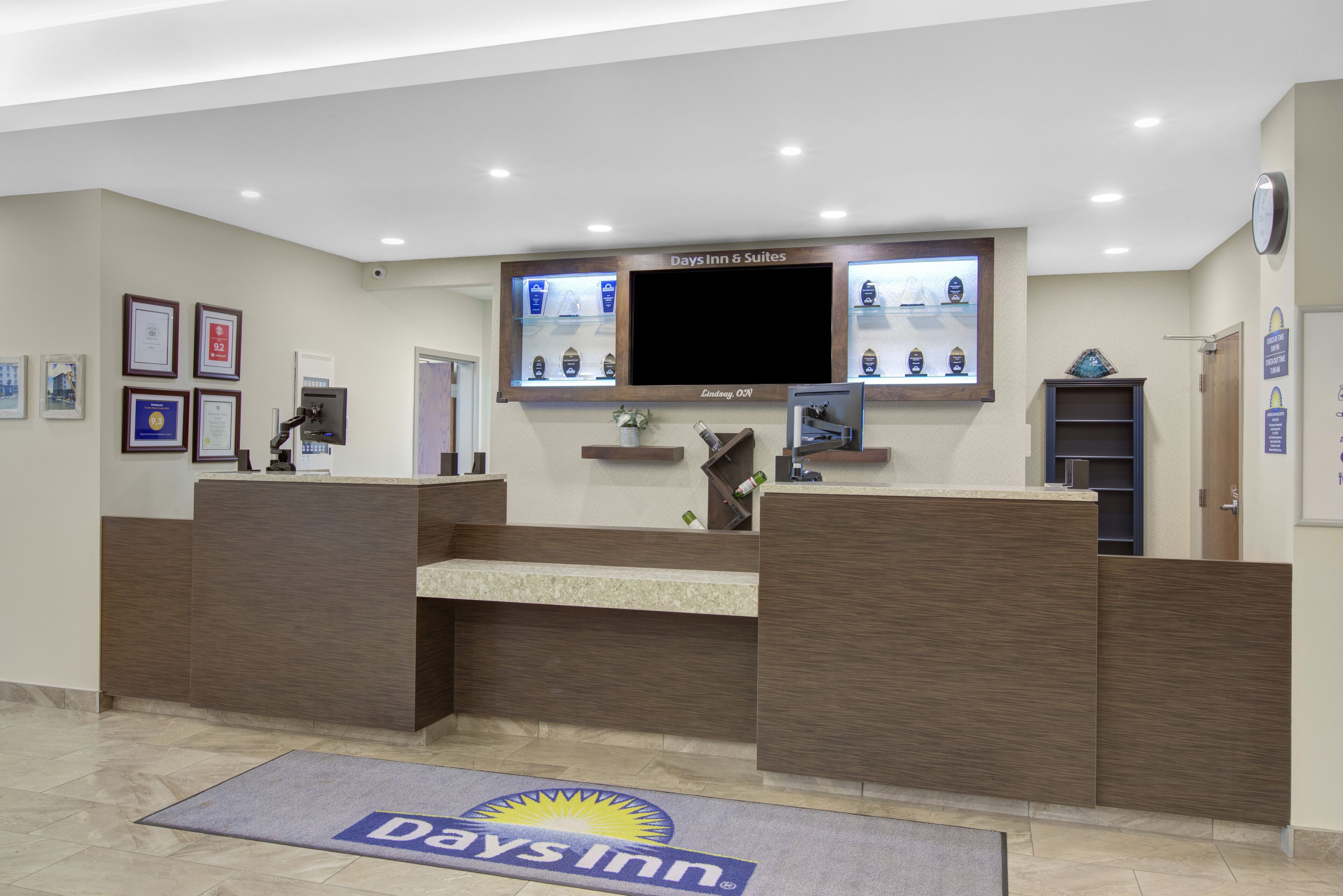 Un'area reception con scrivania, televisione a schermo piatto, certificati incorniciati e il logo sul tappeto.