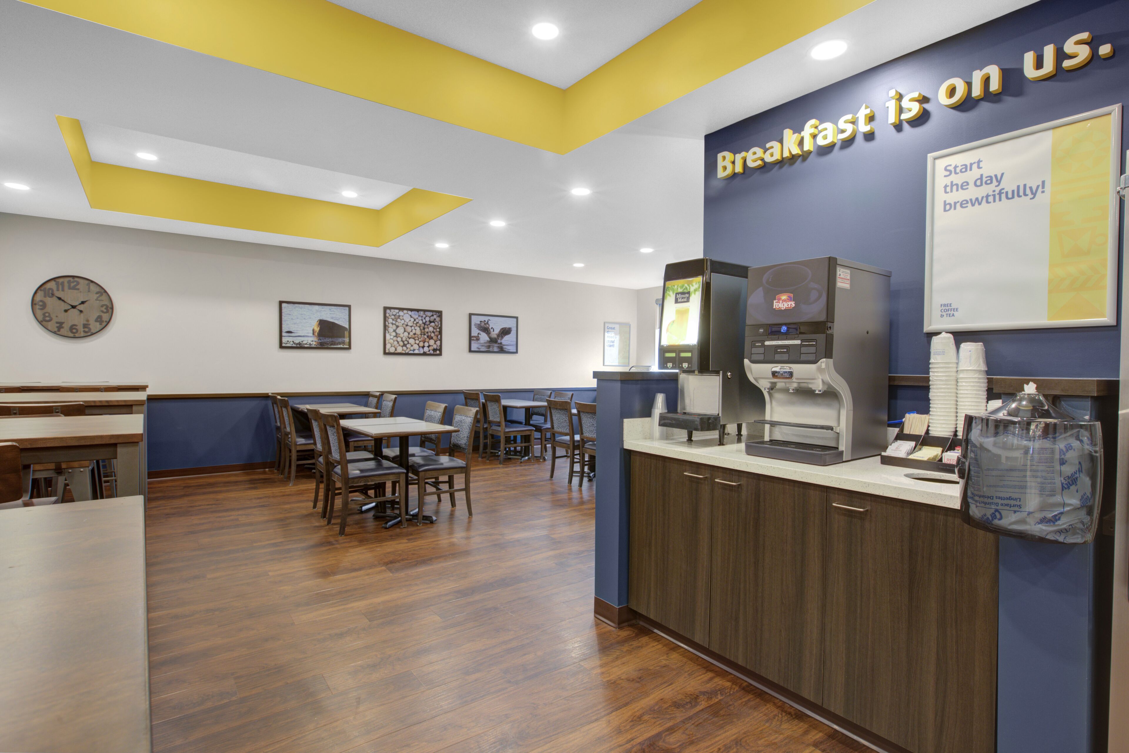 A breakfast area with tables, chairs, a coffee machine, and a clock on the wall.