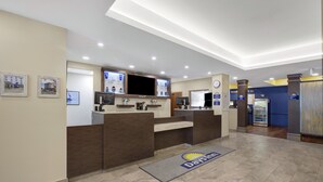 A reception area with a reception desk, a clock, a television, and a refrigerator. - Days Inn & Suites by Wyndham Lindsay (Kawartha Lakes)