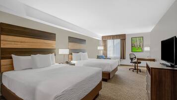 A hotel room with two beds, a desk, a chair, a television, and a painting on the wall.