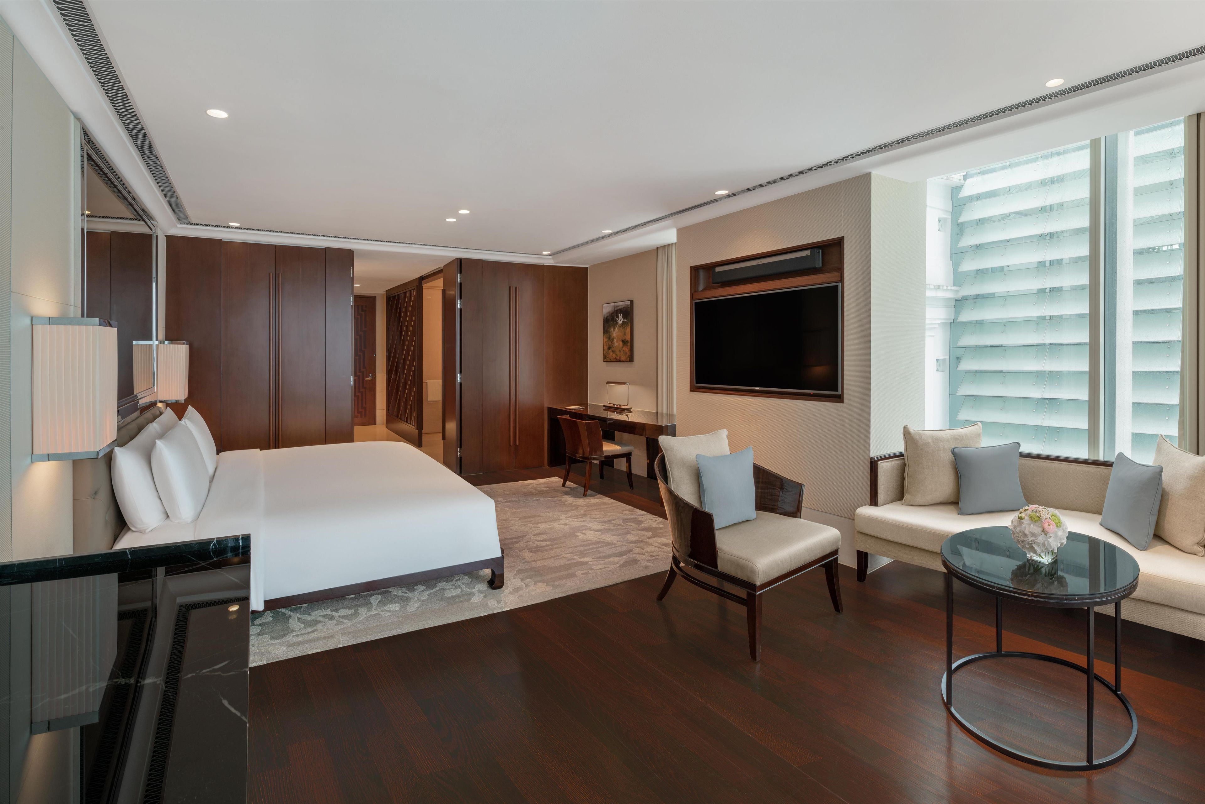 A hotel room with a bed, a desk, a sofa, and a TV.