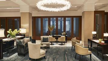 A hotel lobby with a chandelier, seating area, and decorative screens.